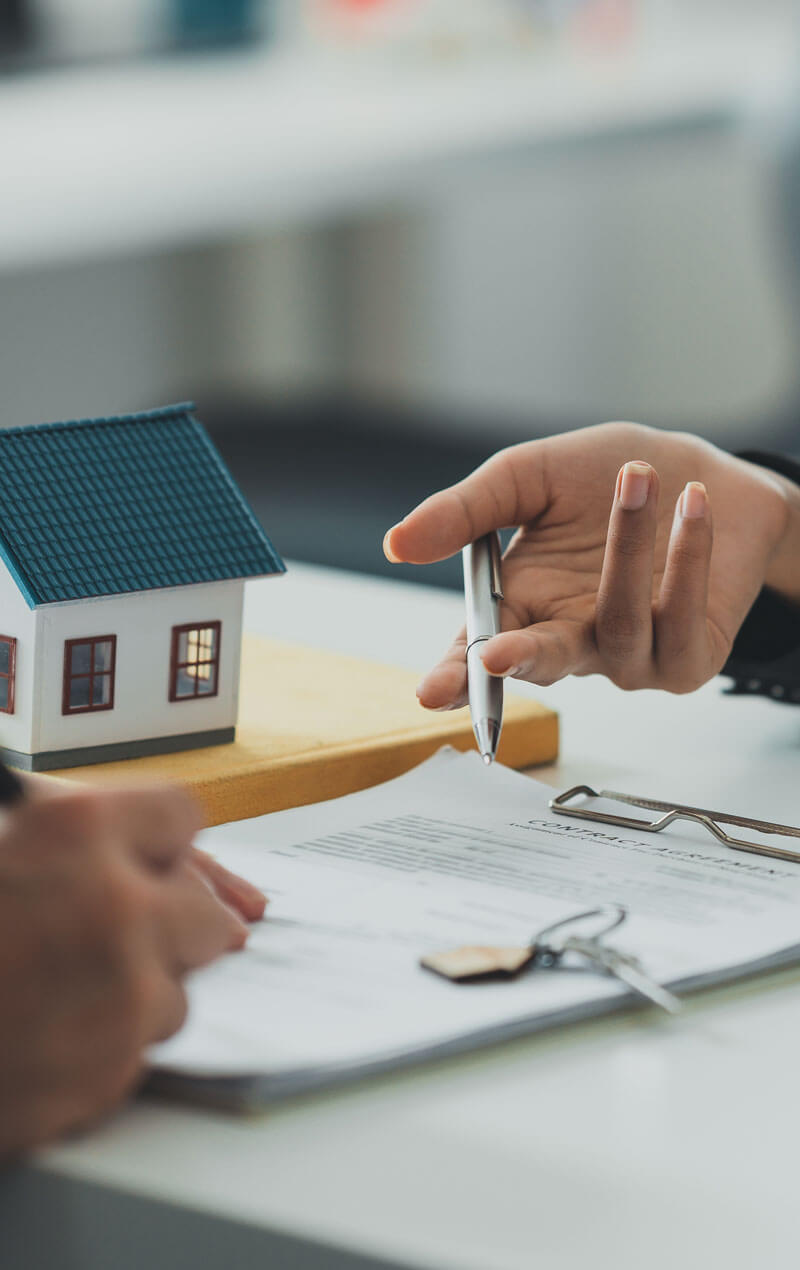 Zwei Menschen sitzen am Tisch und es wir über Immobilien gesprochen, da ein Haus daneben steht